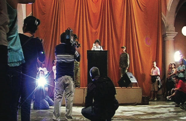 Tatlin’s Whisper #6 (Havana Version), 2009. Stage, podium, microphone, loudspeakers, curtain, 2 people in military fatigues, dove, audience, and 200 disposable cameras, Wilfredo Lam Center, Havana. Courtesy of Berezdivin Collection, San Juan, Puerto Rico. El susurro de Tatlin #6 (version para La Habana), 2009. Plataforma, podio, micrófonos, baffles, telón, dos personas con vestimenta militar de faena, paloma, público y 200 cámaras desechables. Centro Wifredo Lam, La Habana. Cortesía Colección Berezdivin, San Juan, Puerto Rico.